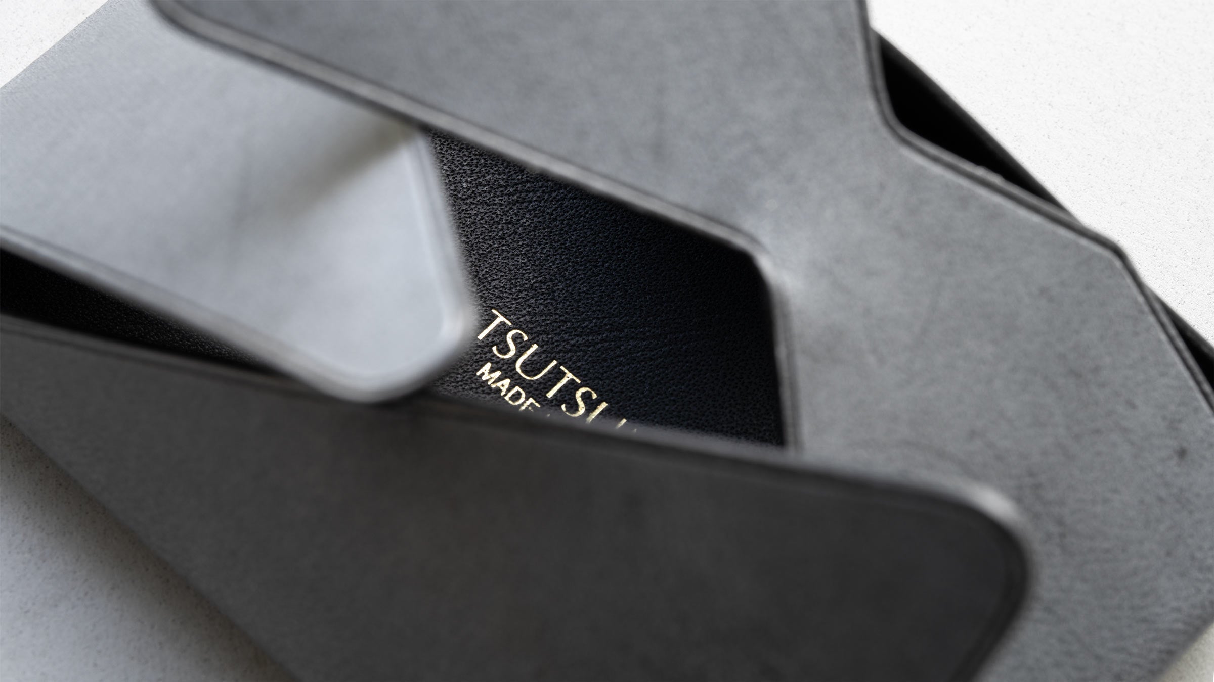 包みの内側に金箔のロゴがのぞく名刺入れ。包むことで生まれる内と外の関係を表す構造。